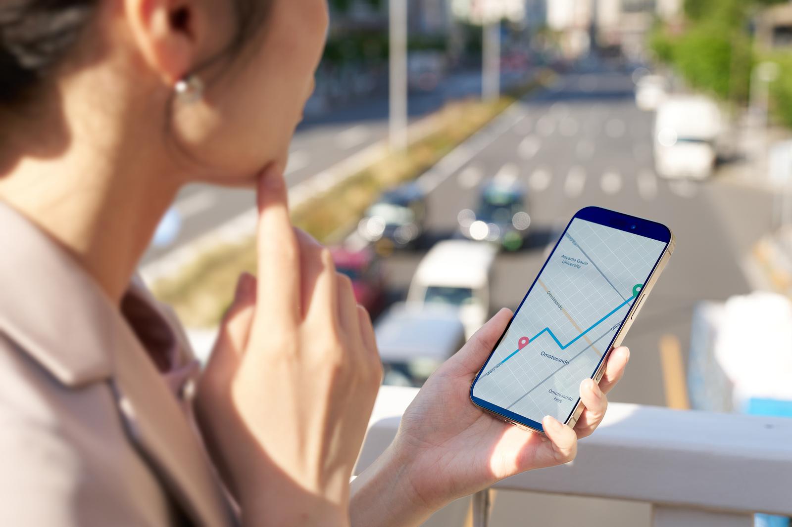 地図アプリを表示したスマートフォンを見る女性